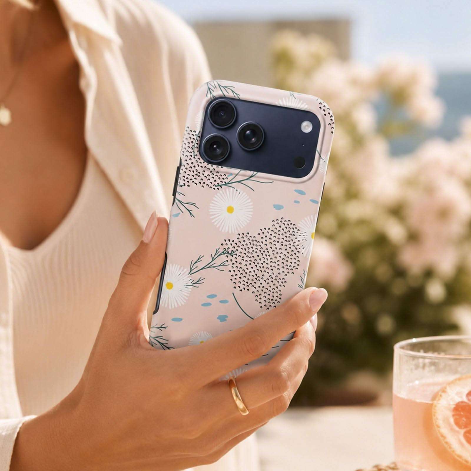 Daisy Haze MagSafe Tough Phone Case with floral and dotted pattern, held in hand outdoors.