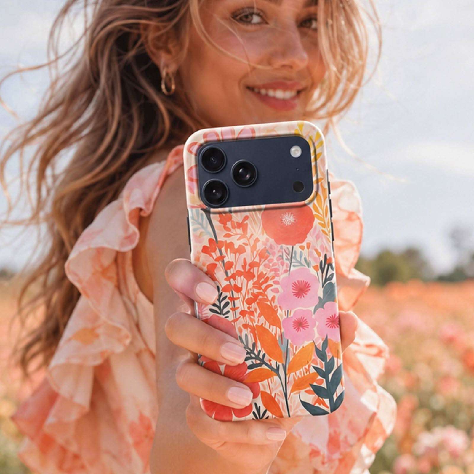 Floral MagSafe phone case with colorful botanical design, held by smiling woman in flower field