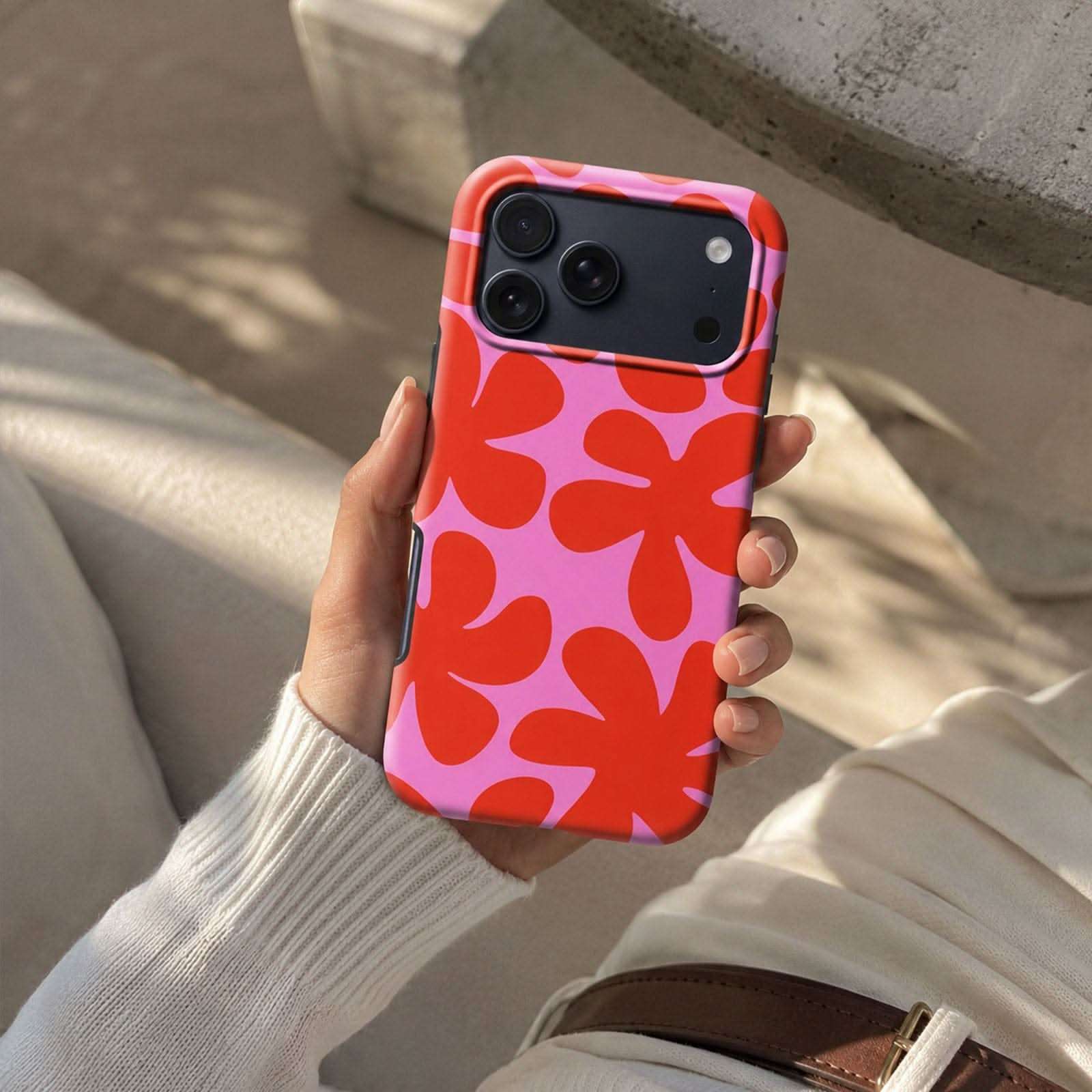Hot Papercut MagSafe Tough Phone Case with red flower pattern on pink background, held in hand.
