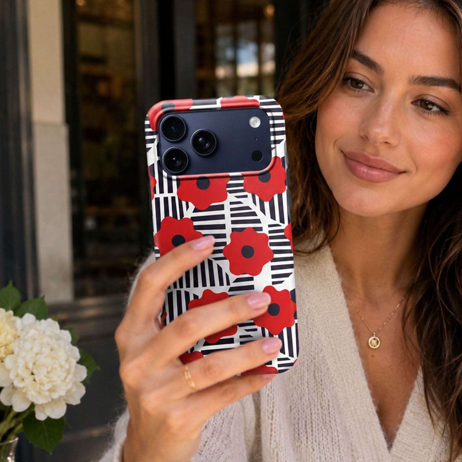 Red poppy flowers with black and white striped pattern on iPhone case with camera cutout.