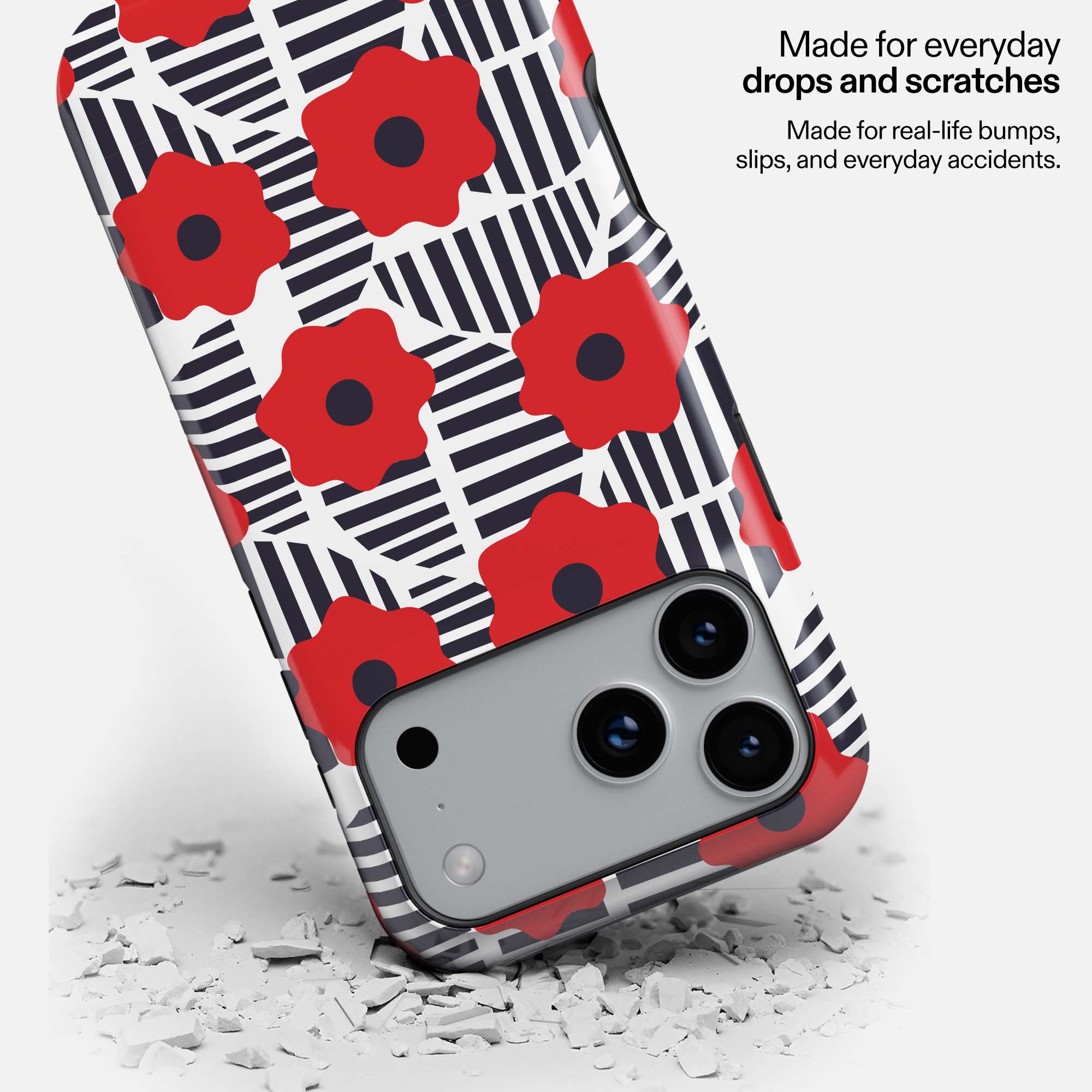 Red and black striped phone case with red flowers, dropped on white debris, showing durability.