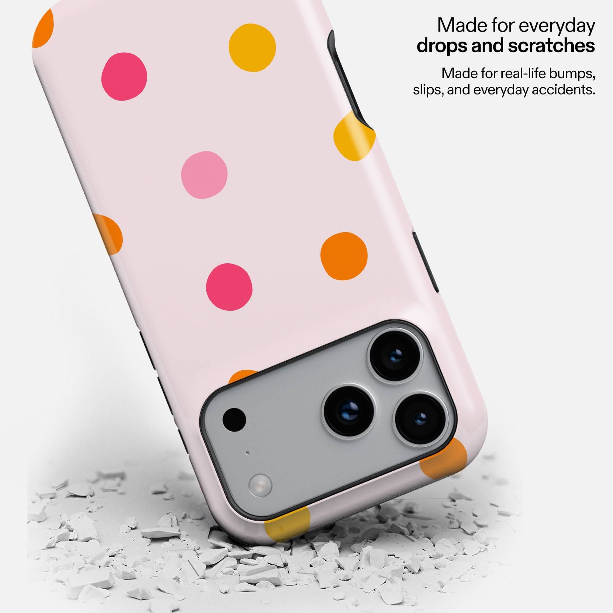 Colorful polka dot phone case in pink, orange, and yellow on light background with protective bumpers.