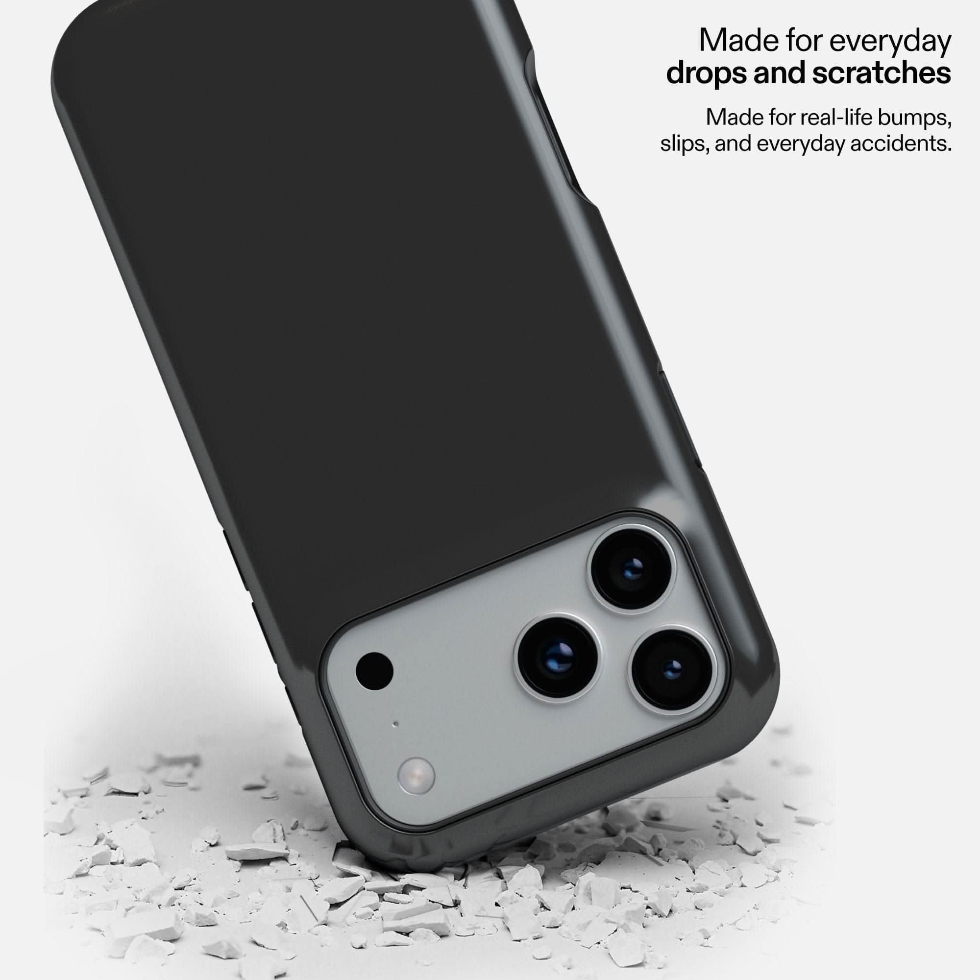 Charcoal MagSafe tough phone case protecting device on debris, showing durability against drops and scratches.