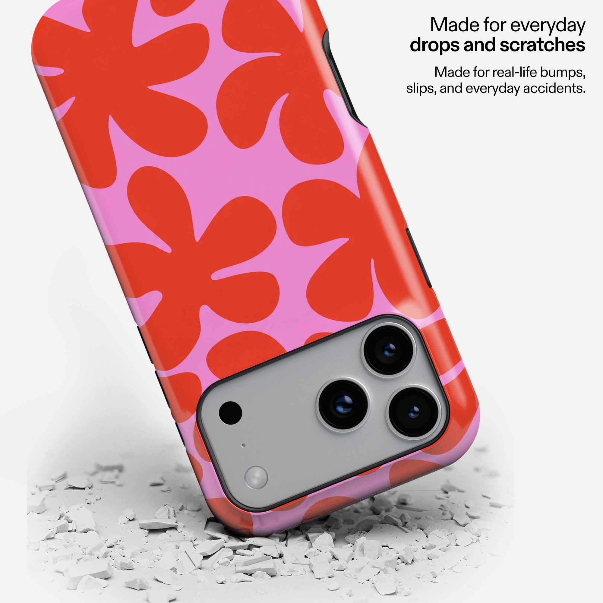 Red and pink floral patterned phone case with camera cutout on white debris background.