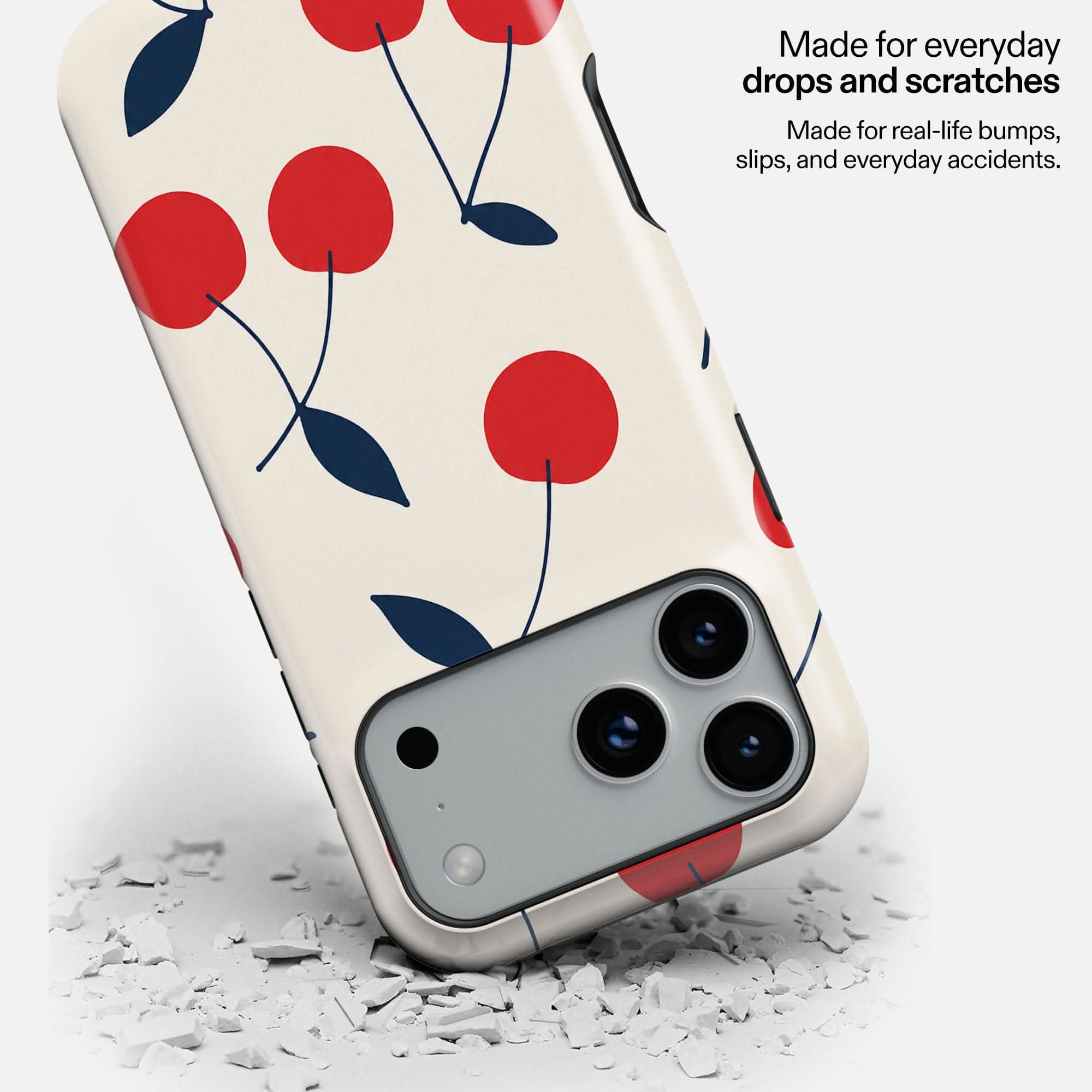 Cream cherry-patterned MagSafe phone case with red circles and navy leaves, displayed on white debris.