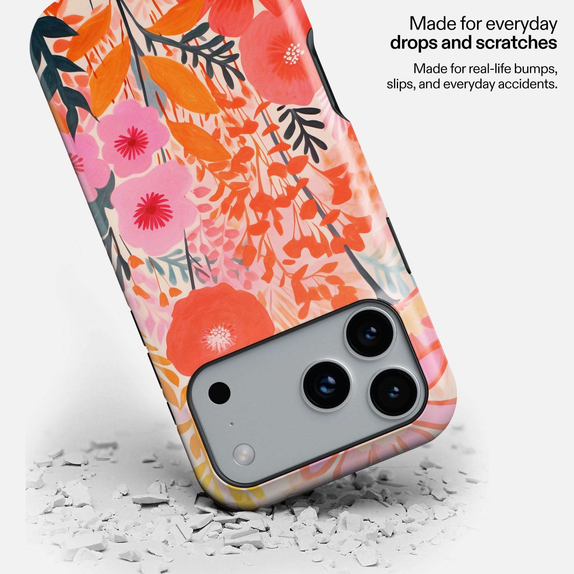 Colorful floral phone case with pink, orange, and red flowers, shown protecting a silver smartphone camera.