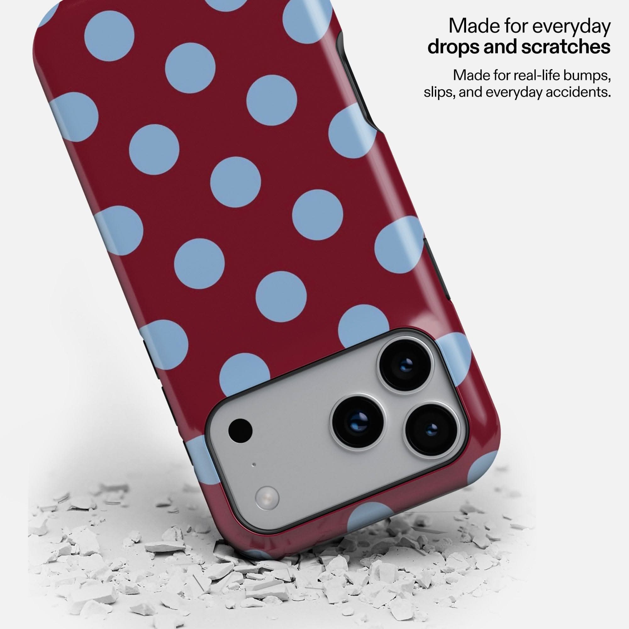 Berry Sky MagSafe Tough Phone Case with blue polka dots, shown dropped on white debris to demonstrate durability.