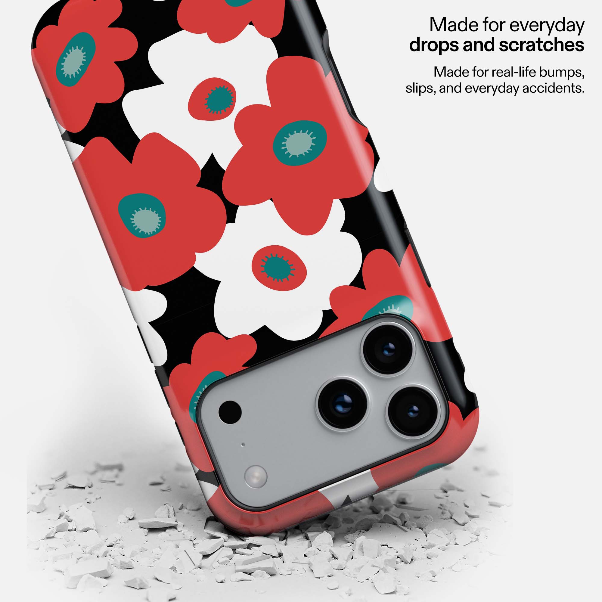 Red and white floral phone case with teal centers on black background, showing durability against white debris.